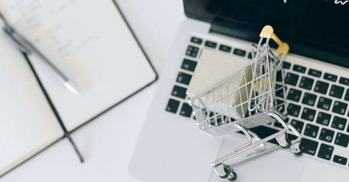 Creative depiction of online shopping with a miniature cart on a laptop keyboard.